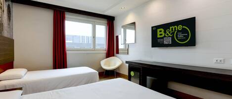 A hotel room with two single beds, a chair, a TV, and a mirror.