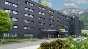 Een modern hotelgebouw met een plat dak, meerdere ramen en een bord dat aangeeft dat het een B&B hotel is.