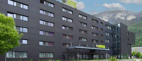 Un hôtel moderne, avec un toit plat, de nombreuses fenêtres et une enseigne indiquant qu’il s’agit d’un hôtel proposant également un service de chambre et de petit-déjeuner.