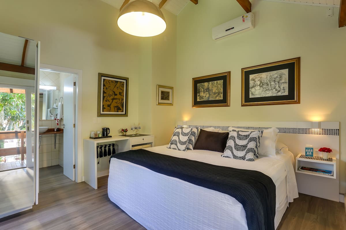 Ein Schlafzimmer mit einem großen Bett, einem Nachttisch, einem Deckenventilator und einer Wand-Klimaanlage.