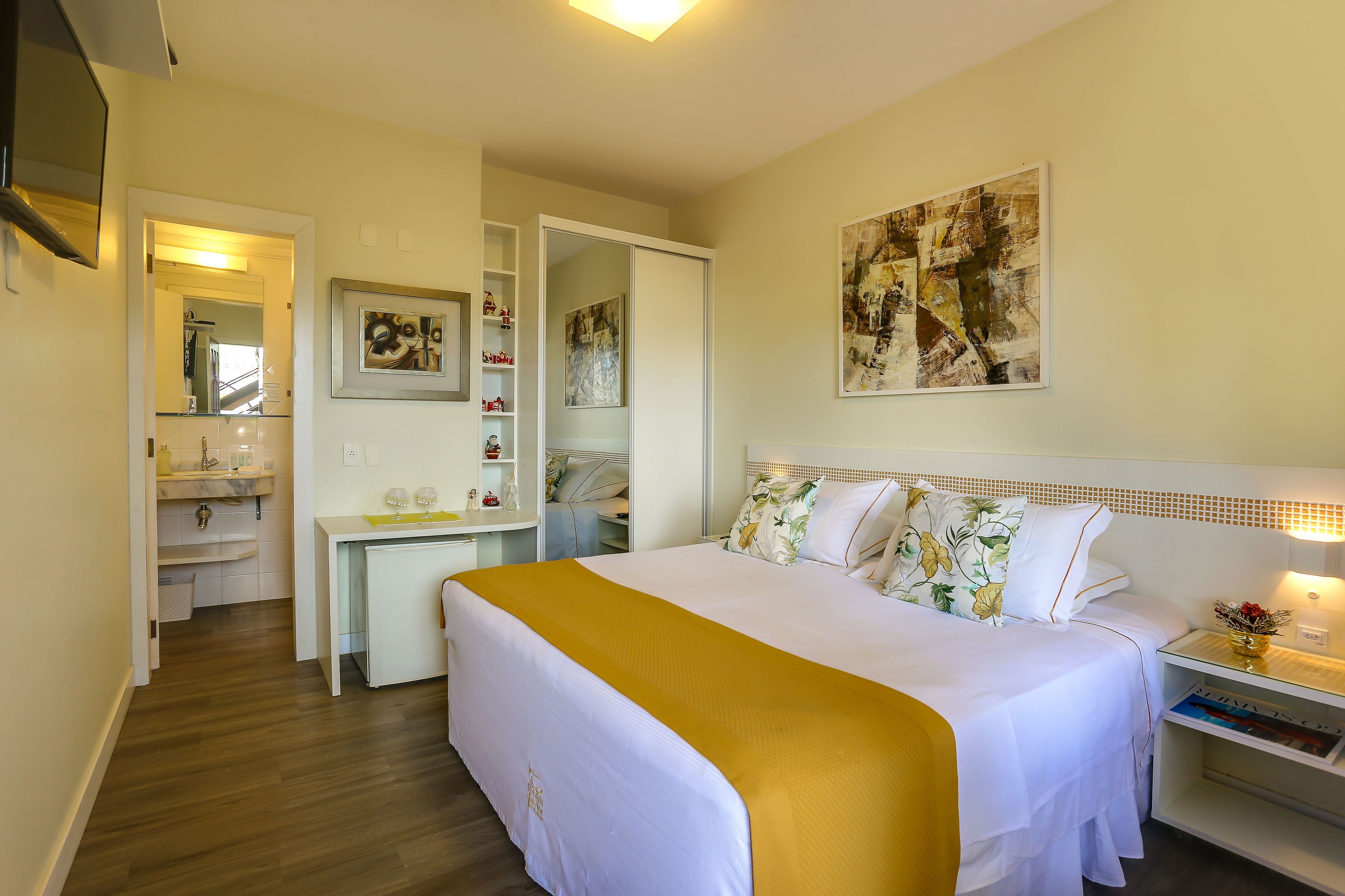 A hotel room with a bed, bedside table, and a desk with a chair.