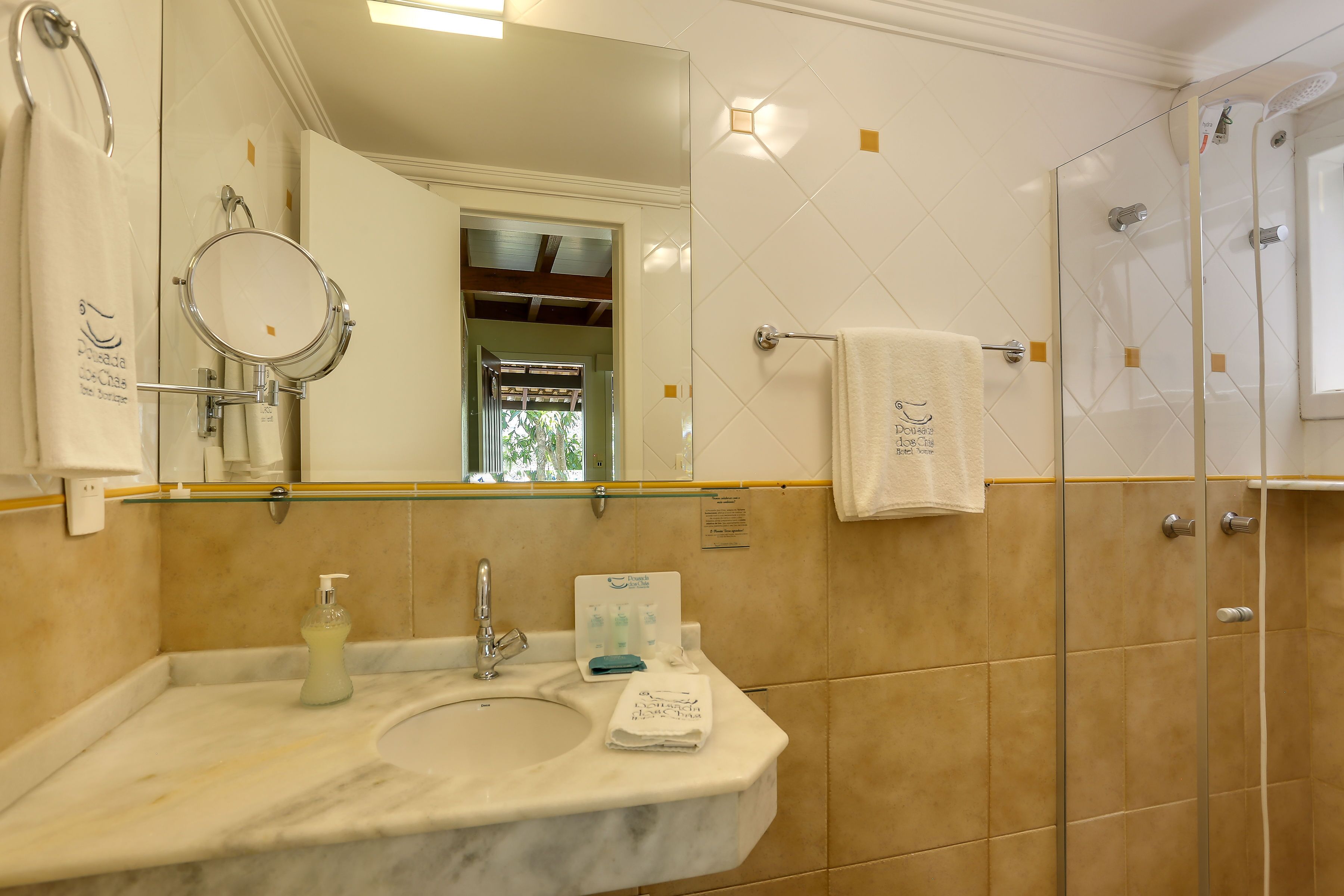A bathroom with a marble sink, a mirror, a towel rack, and a glass shower enclosure.