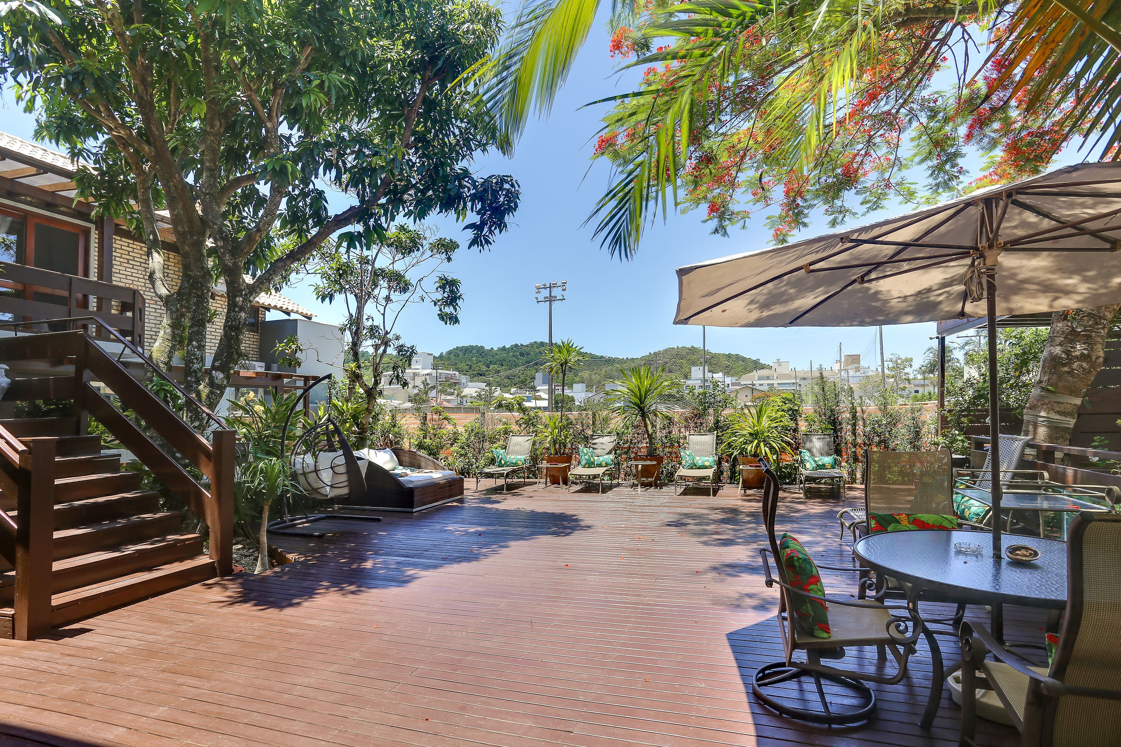 A wooden deck with outdoor furniture, a staircase, and a view of a cityscape in the background.