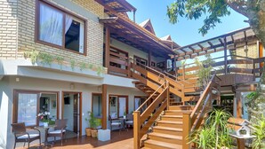 A multi-story building with a wooden staircase, outdoor seating area, and potted plants. - Nova Pousada dos Chás (Florianópolis)
