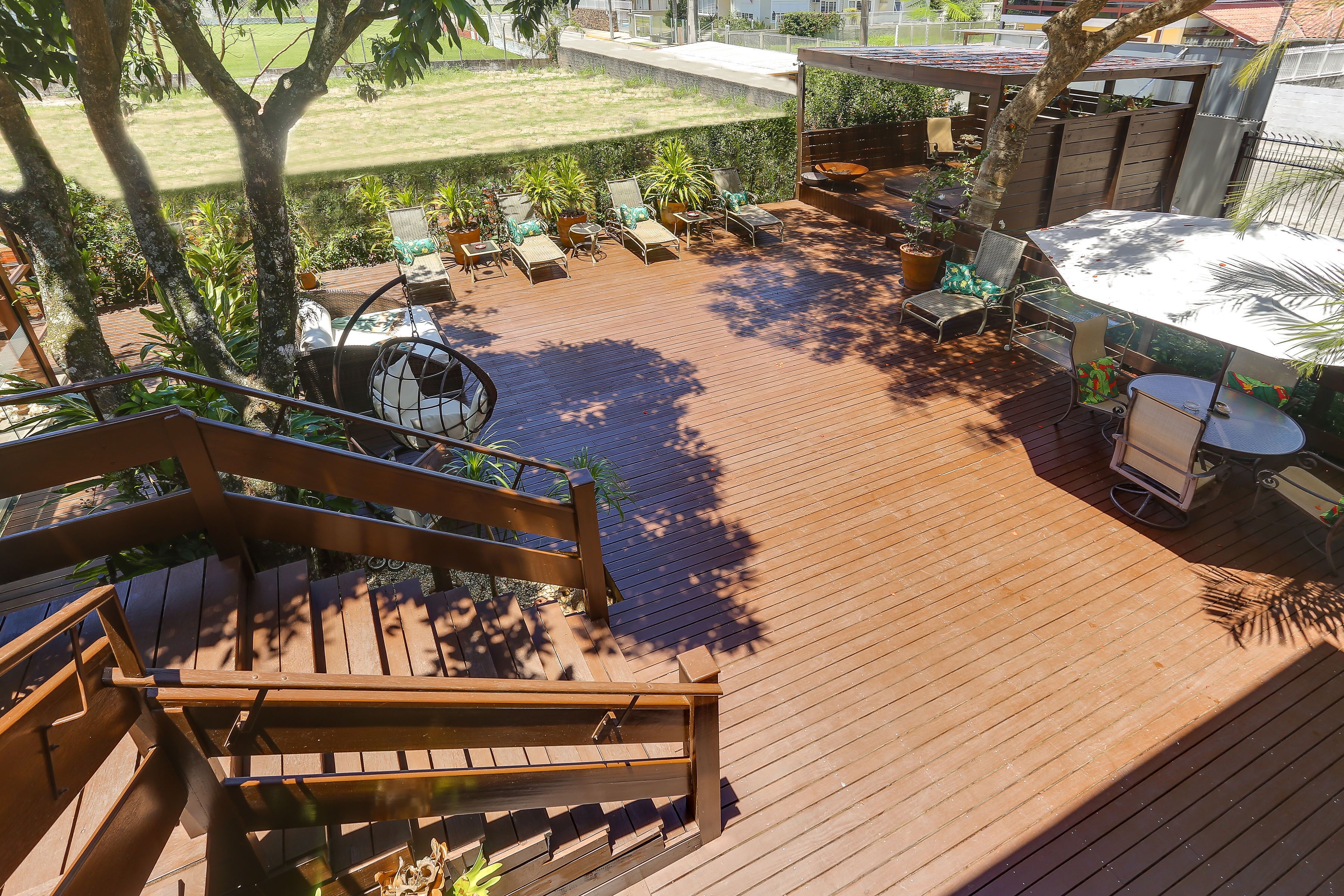 A wooden deck with outdoor furniture, including chairs and a table, surrounded by potted plants.