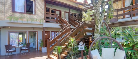 A multi-story house with a wooden deck, outdoor seating, and a hanging chair.