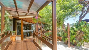 A wooden deck with a glass railing, surrounded by potted plants and greenery. - Nova Pousada dos Chás (Florianópolis)