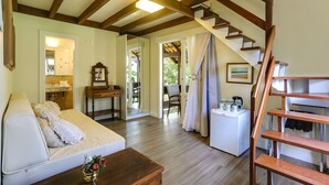 A cozy living room with a sofa, a wooden coffee table, and a staircase leading to another room. - Nova Pousada dos Chás (Florianópolis)