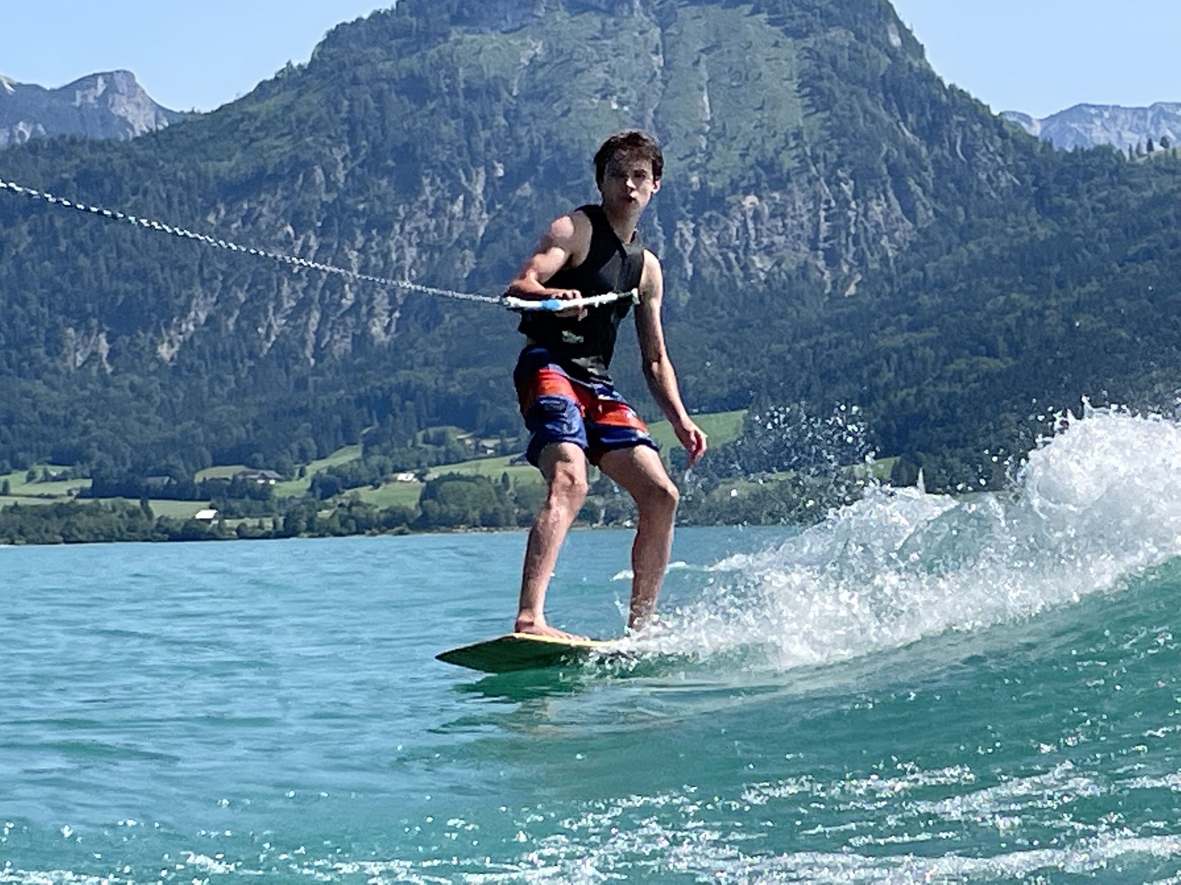 A person wakeboarding on a lake with mountains in the background.