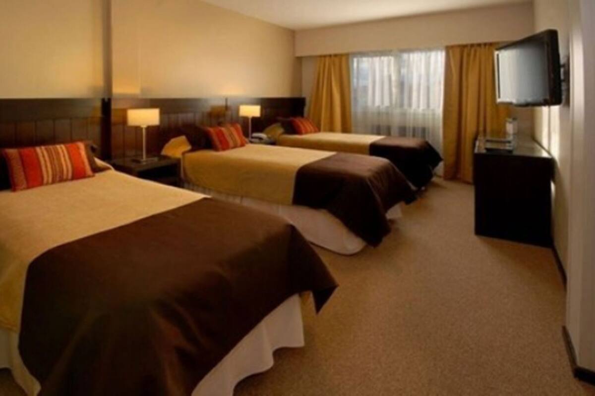 Une chambre d’hôtel avec deux lits, une télévision et une fenêtre avec des rideaux.