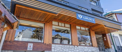 Un hôtel à plusieurs étages, doté d’une façade en pierre, d’une entrée en bois et d’une enseigne indiquant « Hôtel Carlos V ».
