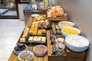 Buffet com diversas opções de comida, incluindo doces, frutas e cereais.