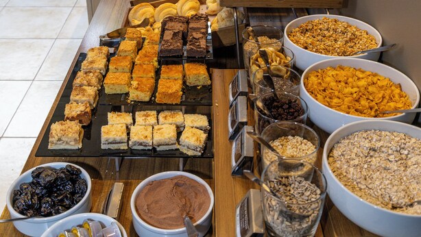 Un buffet proposant une variété d’aliments, notamment des pâtisseries, des fruits et des céréales.