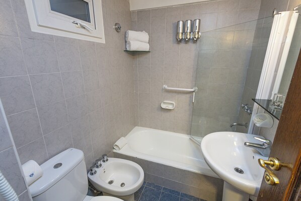 A bathroom with a toilet, bidet, bathtub, and two sinks.