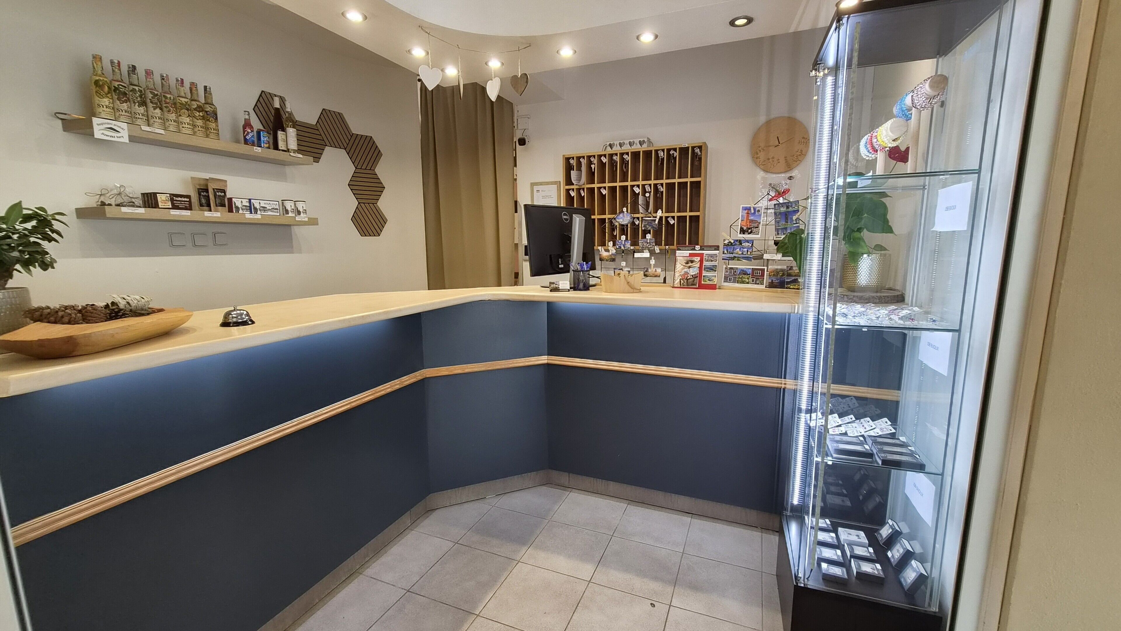 Un área de recepción con un mostrador curvo, una exhibición de botellas de vino, un reloj y una vitrina de vidrio con joyería.