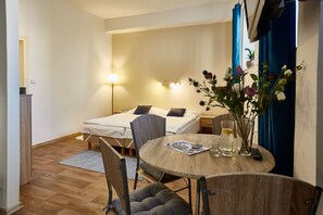 A compact hotel room with a bed, a small table with a vase of flowers, a lamp, and a chair. - Hotel Rehavital (Jablonec nad Nisou)