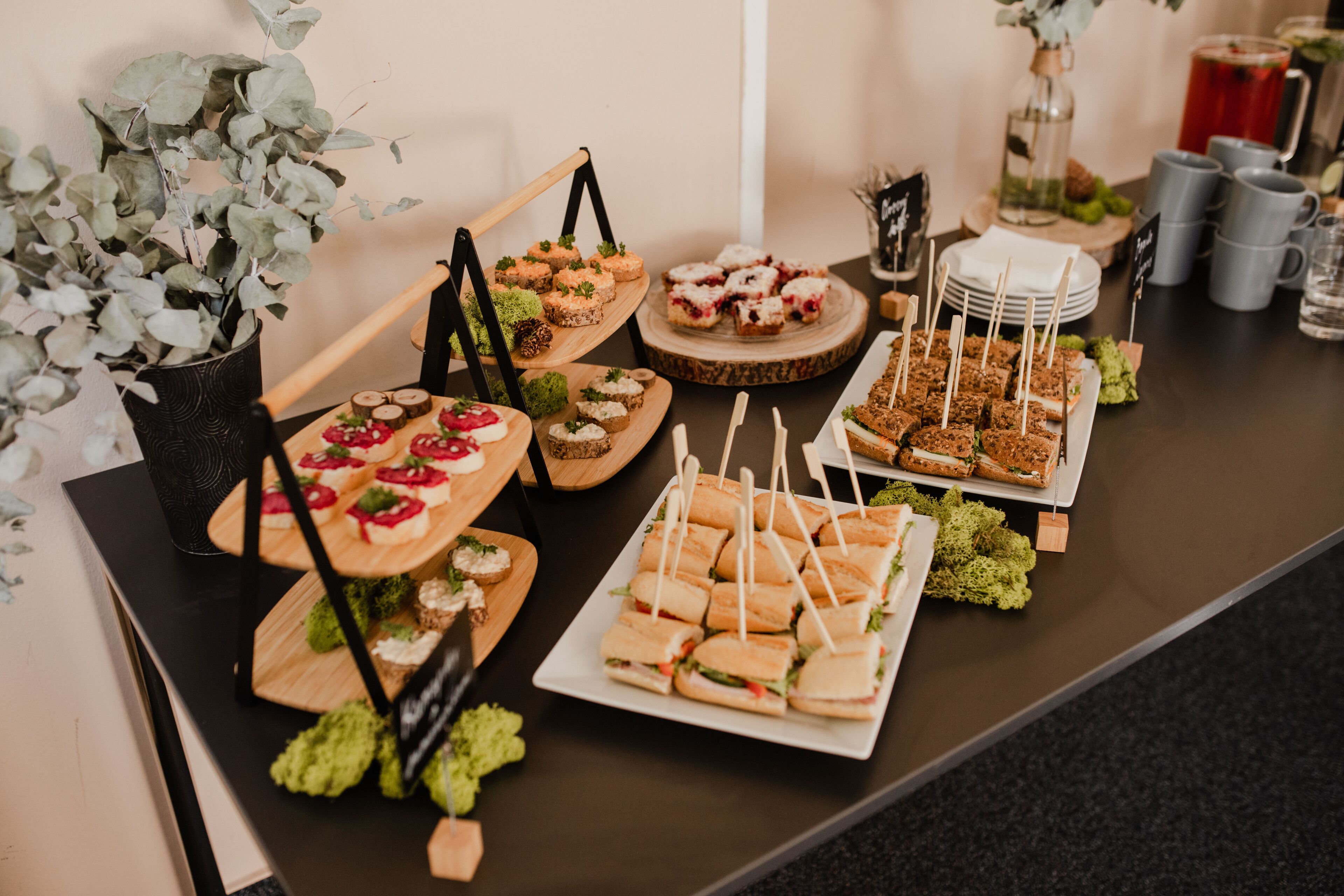 A buffet table with various food items, including sandwiches, desserts, and appetizers.