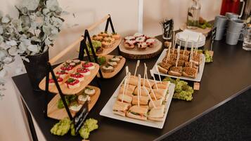 A buffet table with various food items, including sandwiches, desserts, and appetizers.
