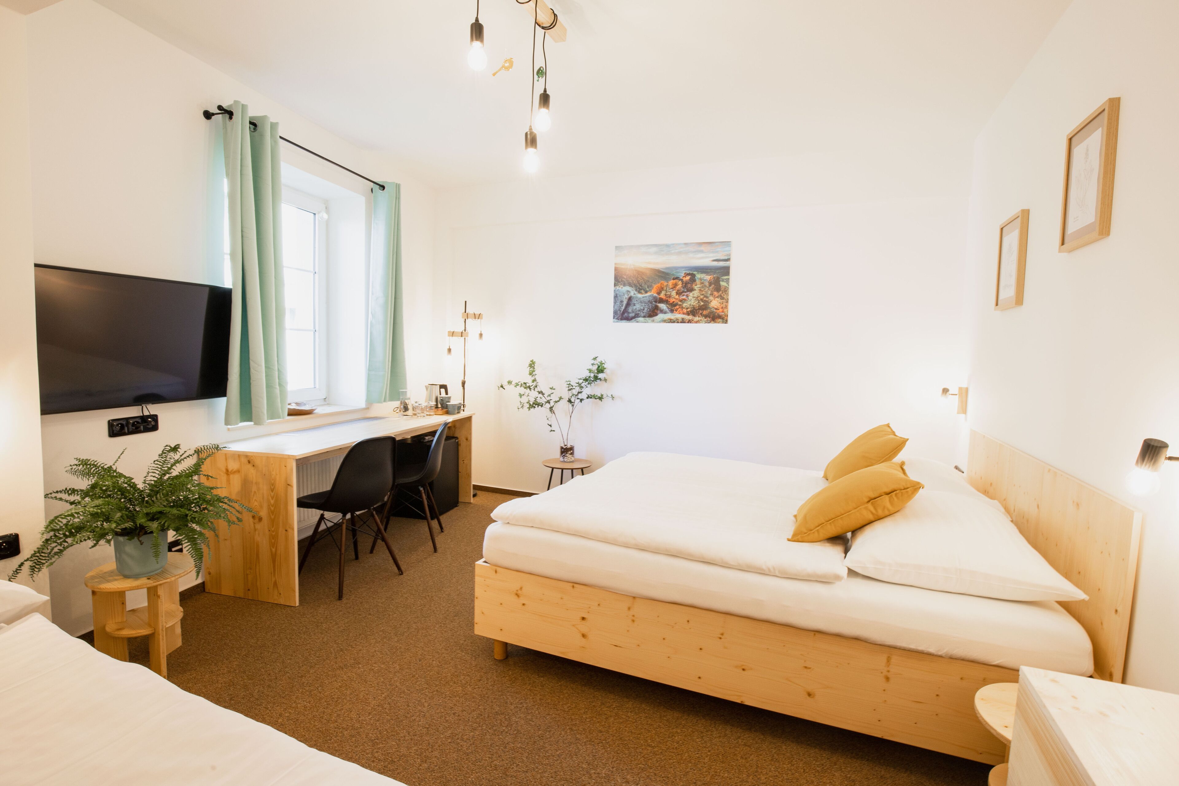 A hotel room with a wooden bed, a desk with a chair, a television, and a window with curtains.