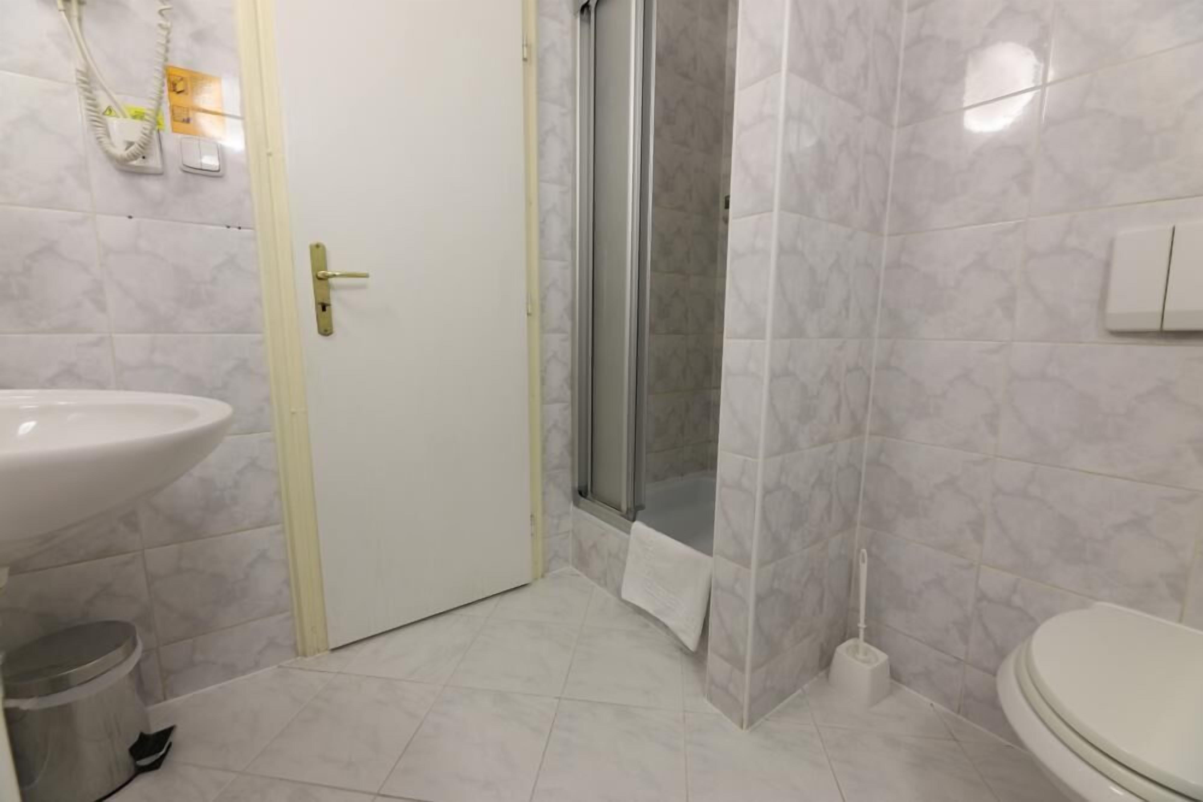 A bathroom with a white sink, toilet, and shower area.