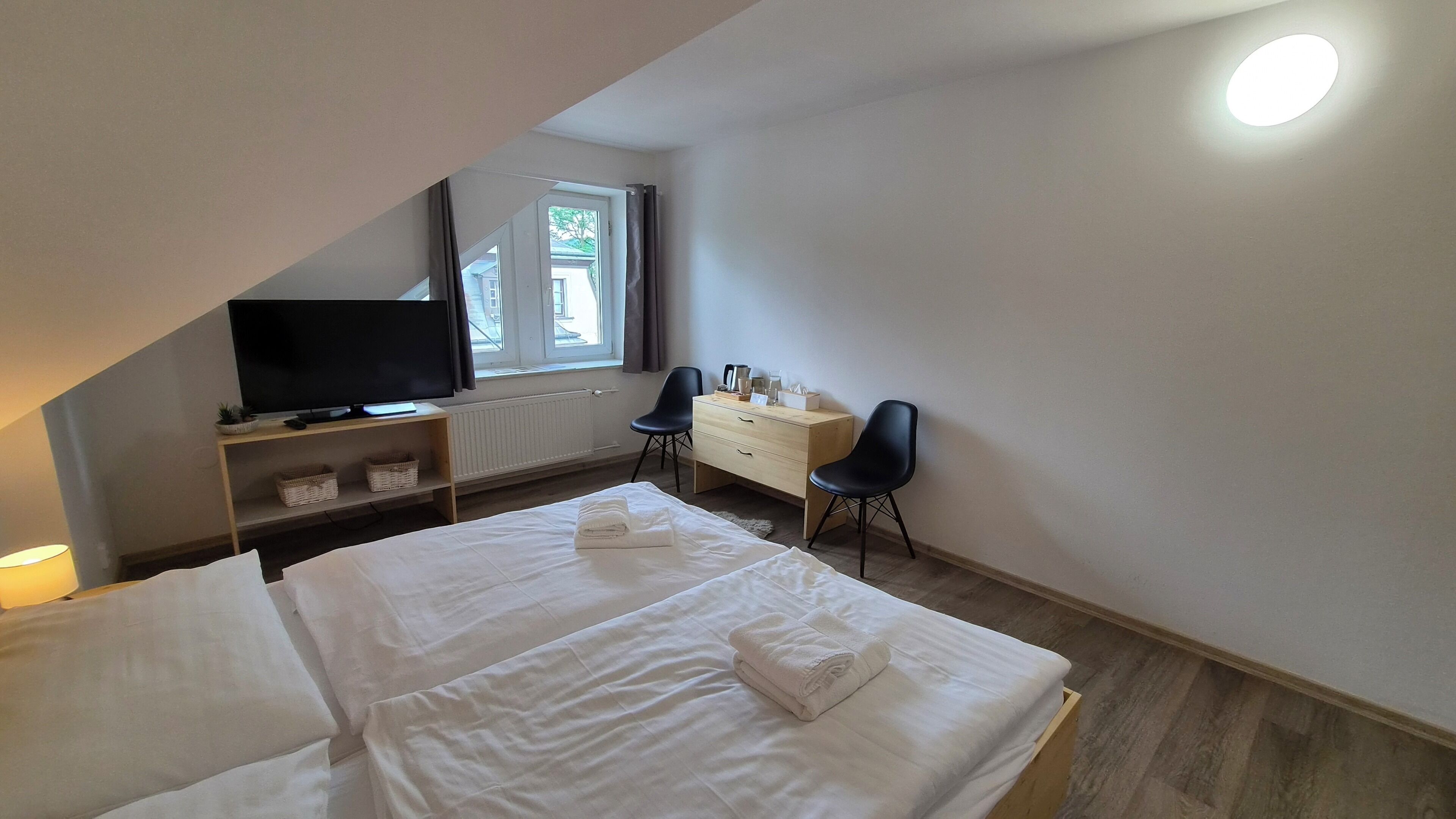 Una habitación de hotel con una cama, un escritorio, una silla, un televisor y una ventana.