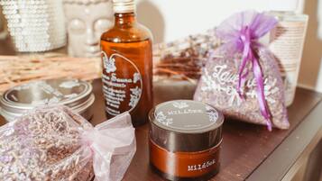 Una mesa de madera con diversos objetos, incluyendo un tarro etiquetado “Milady”, una botella y una bolsa de regalo atada con un lazo.
