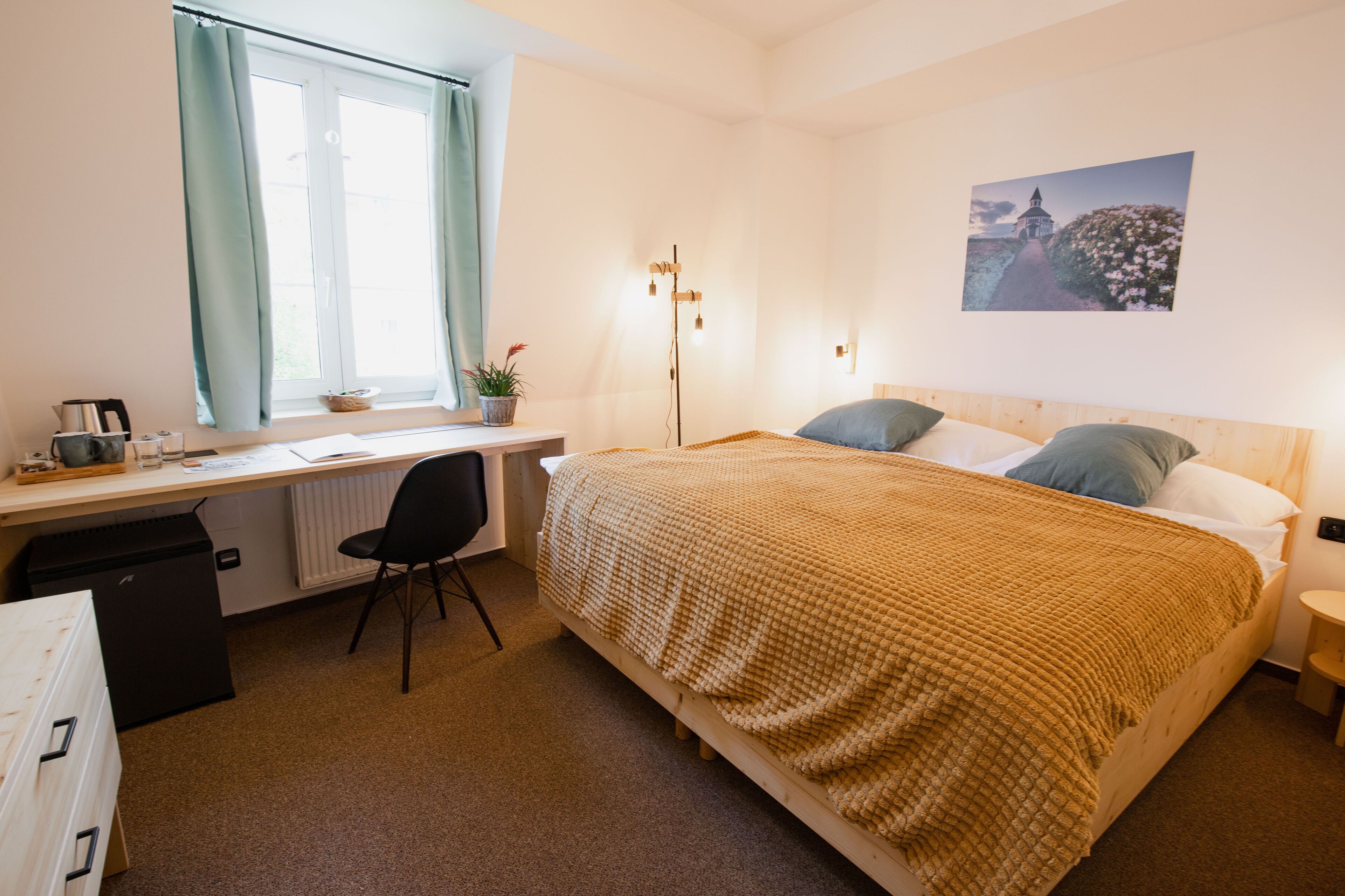 Un dormitorio con cama, escritorio, silla y radiador.