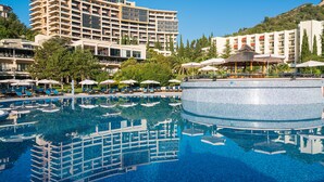 A hotel with a large pool, multiple balconies, and lush greenery.