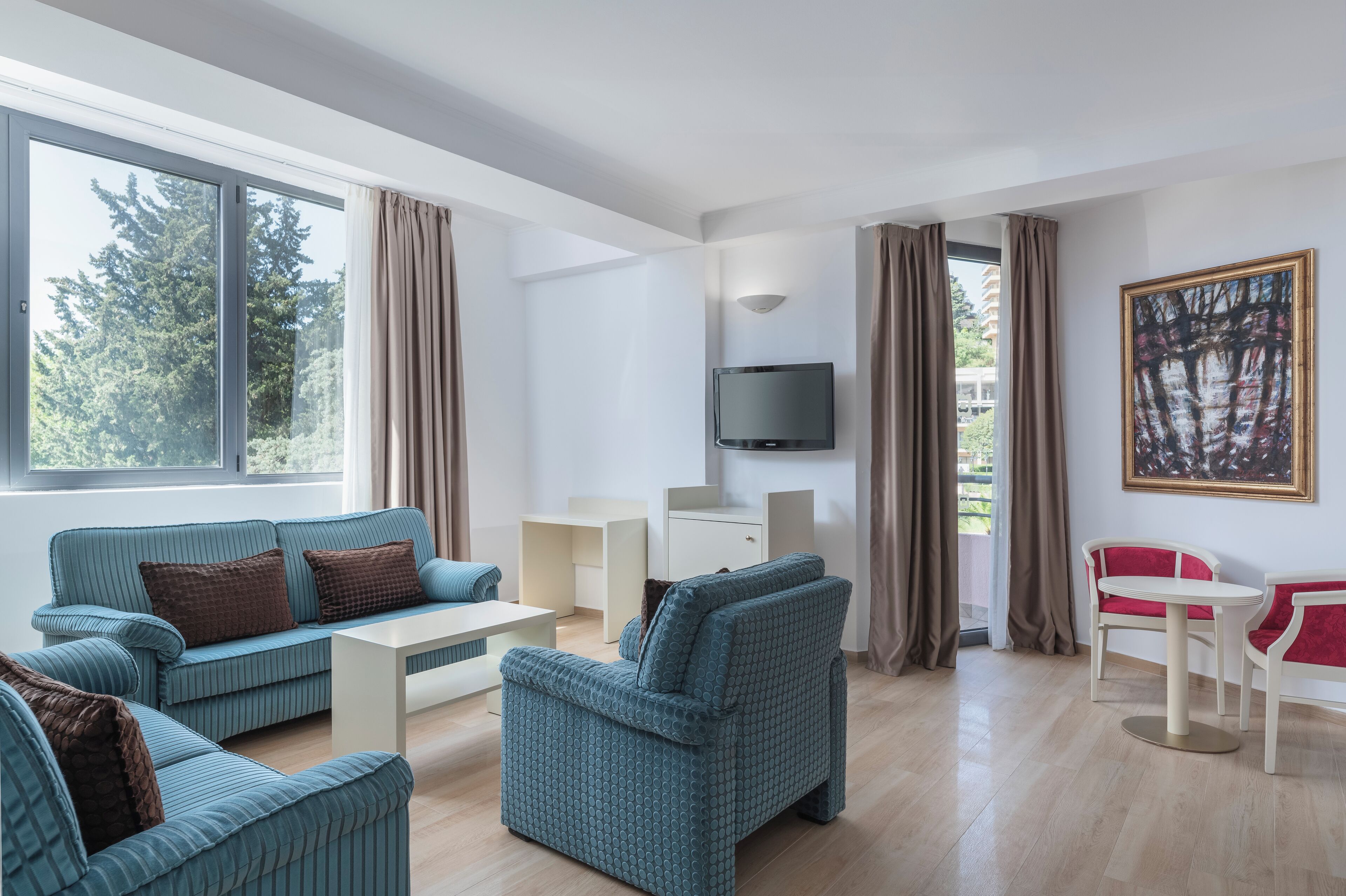 Een moderne zithoek met een bank, fauteuils, een salontafel en een televisie.