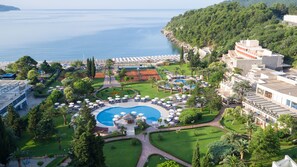 Un resort con piscina central, tumbonas y vista al mar.