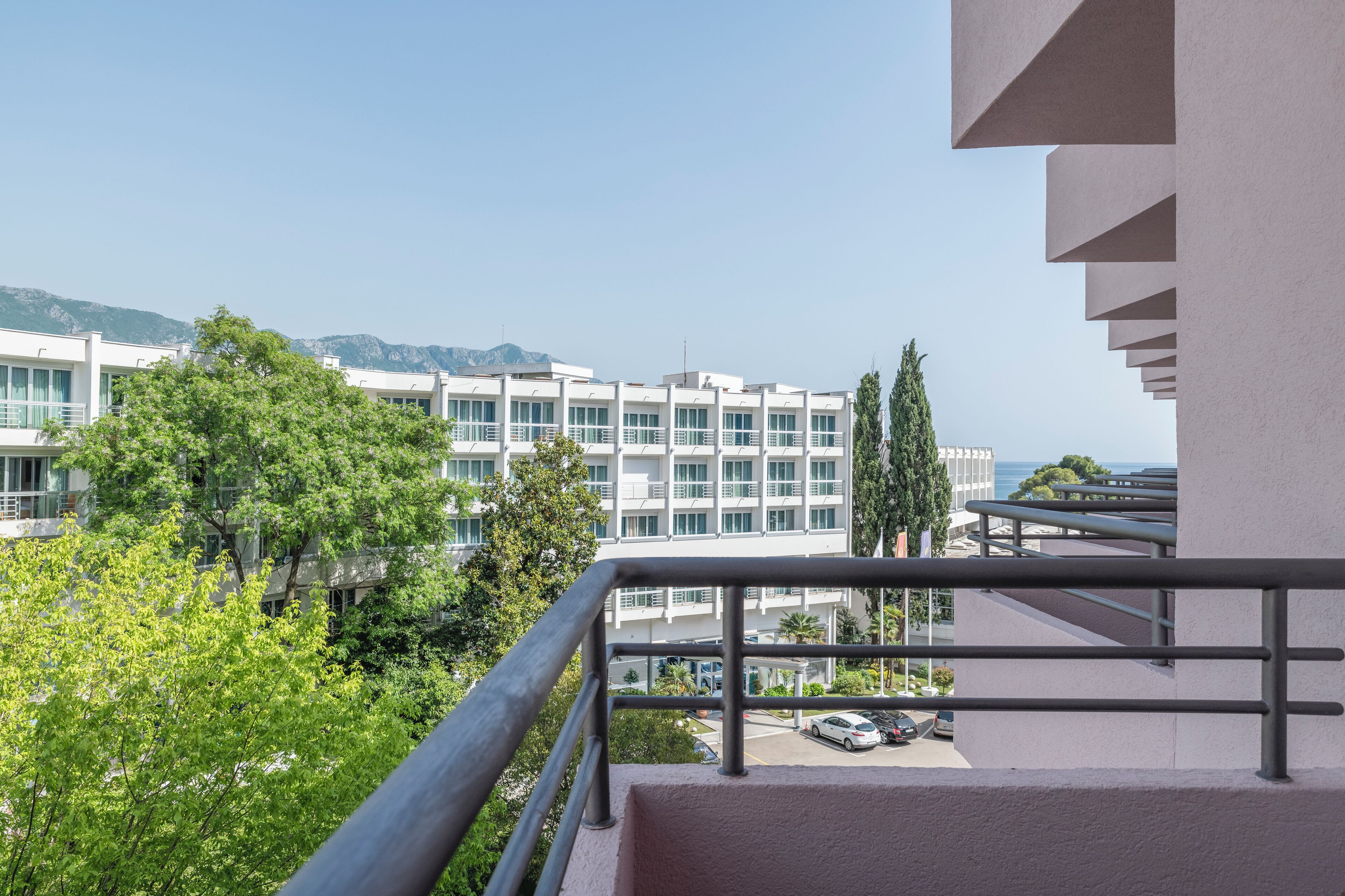 Un edificio moderno con balcón, vegetación y vistas despejadas al mar.