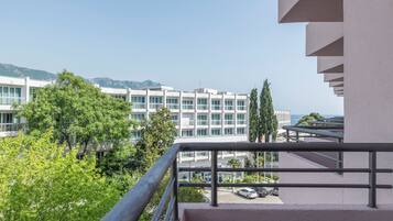 Un edificio moderno con balcón, vegetación y vistas despejadas al mar.