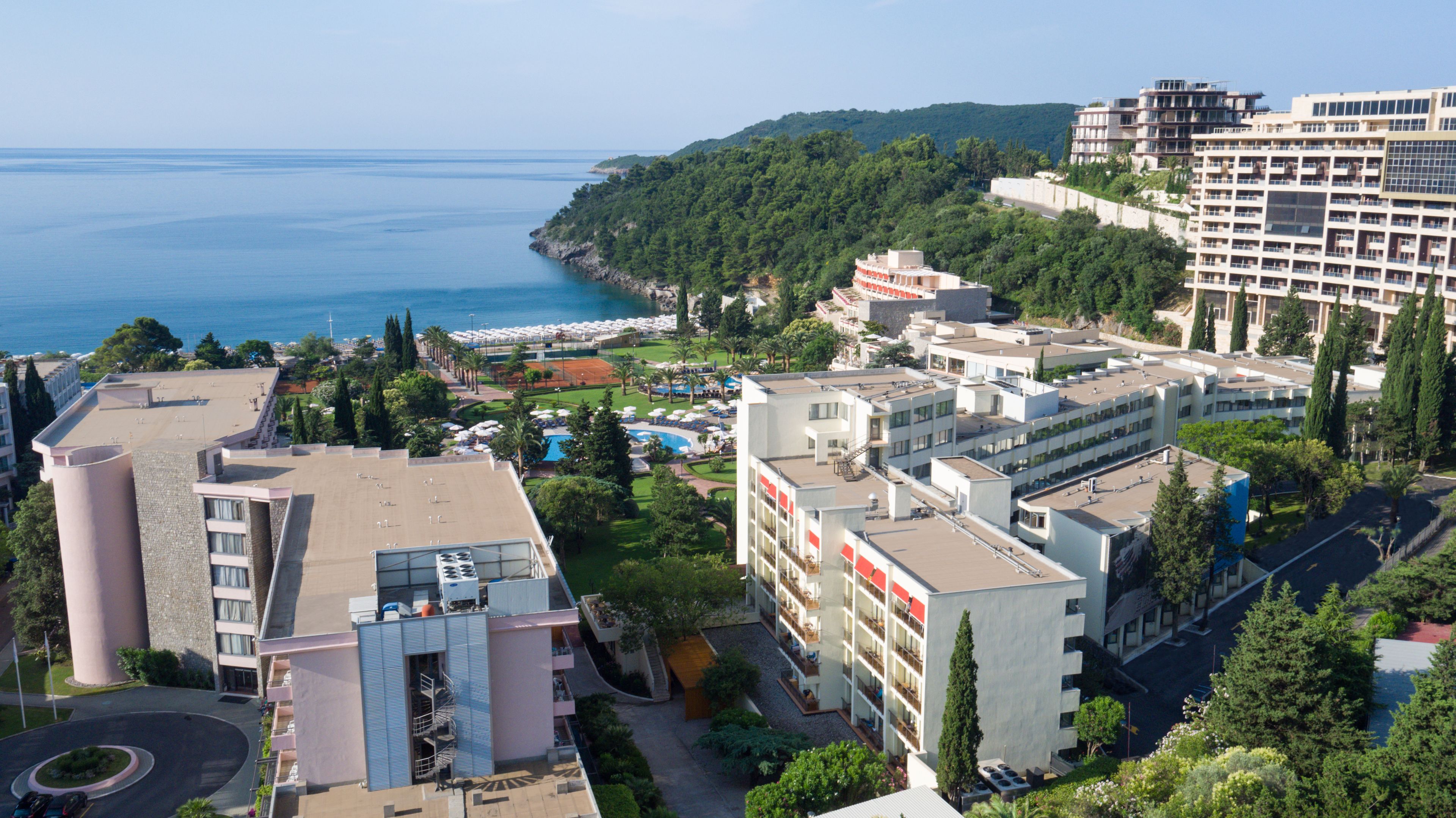 Un hotel costero con varias construcciones, una zona de piscina y vistas al mar.