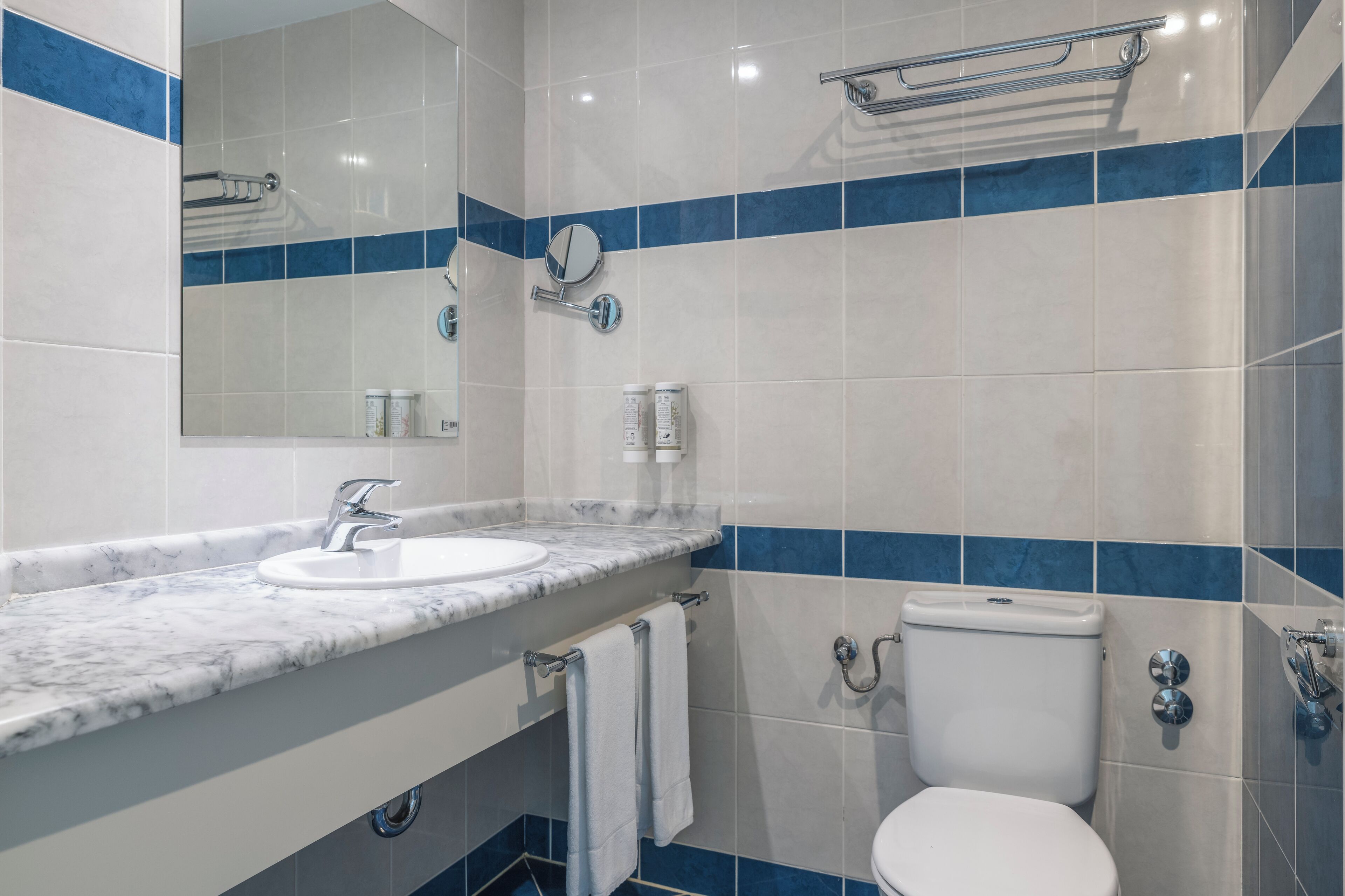 A bathroom with a marble sink, a toilet, and a mirror.