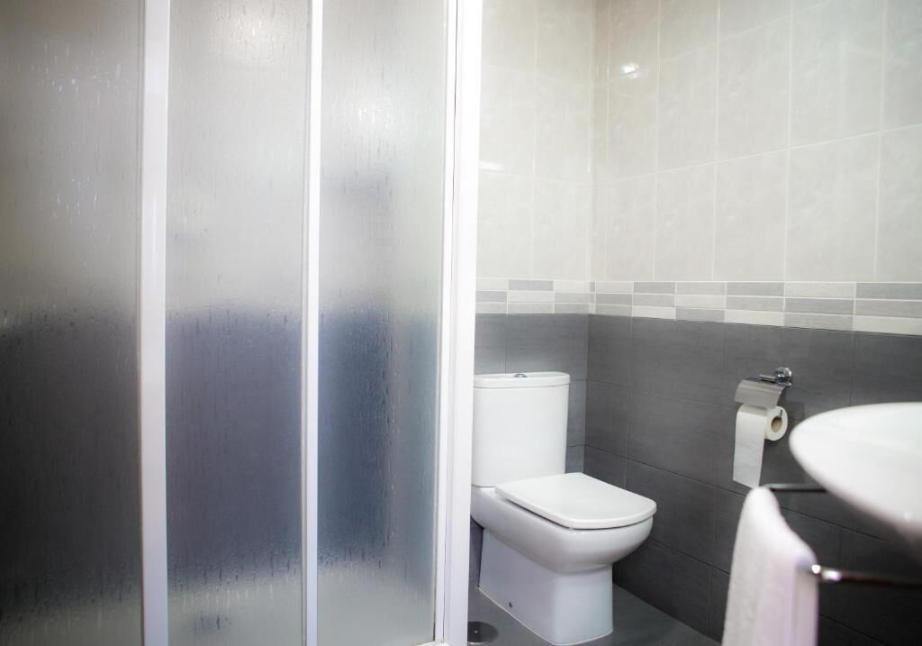A bathroom with a toilet, a sink, and a shower area.