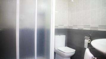 A bathroom with a toilet, a sink, and a shower area.