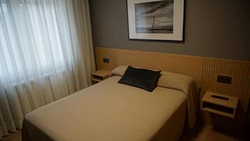 Una habitación de hotel con una cama grande, una mesita de noche, un control remoto y un cuadro en la pared.