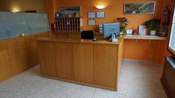 Una reception con una scrivania, una pianta e certificati incorniciati al muro.