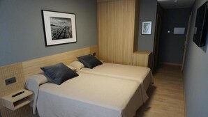 A neatly arranged hotel room with a bed, bedside tables, and a framed picture on the wall. - Europa (Arteixo)