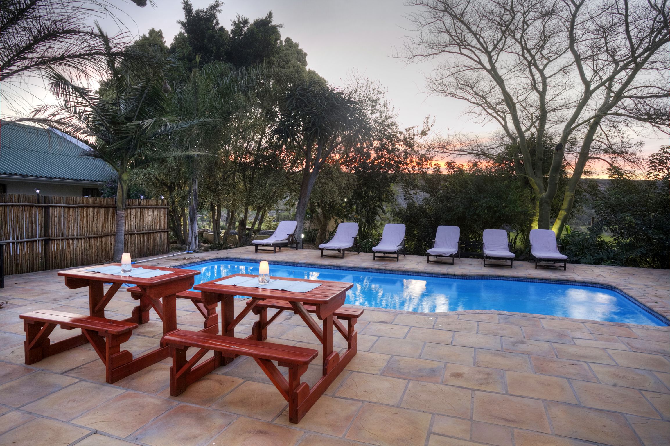A swimming pool with lounge chairs and picnic tables.
