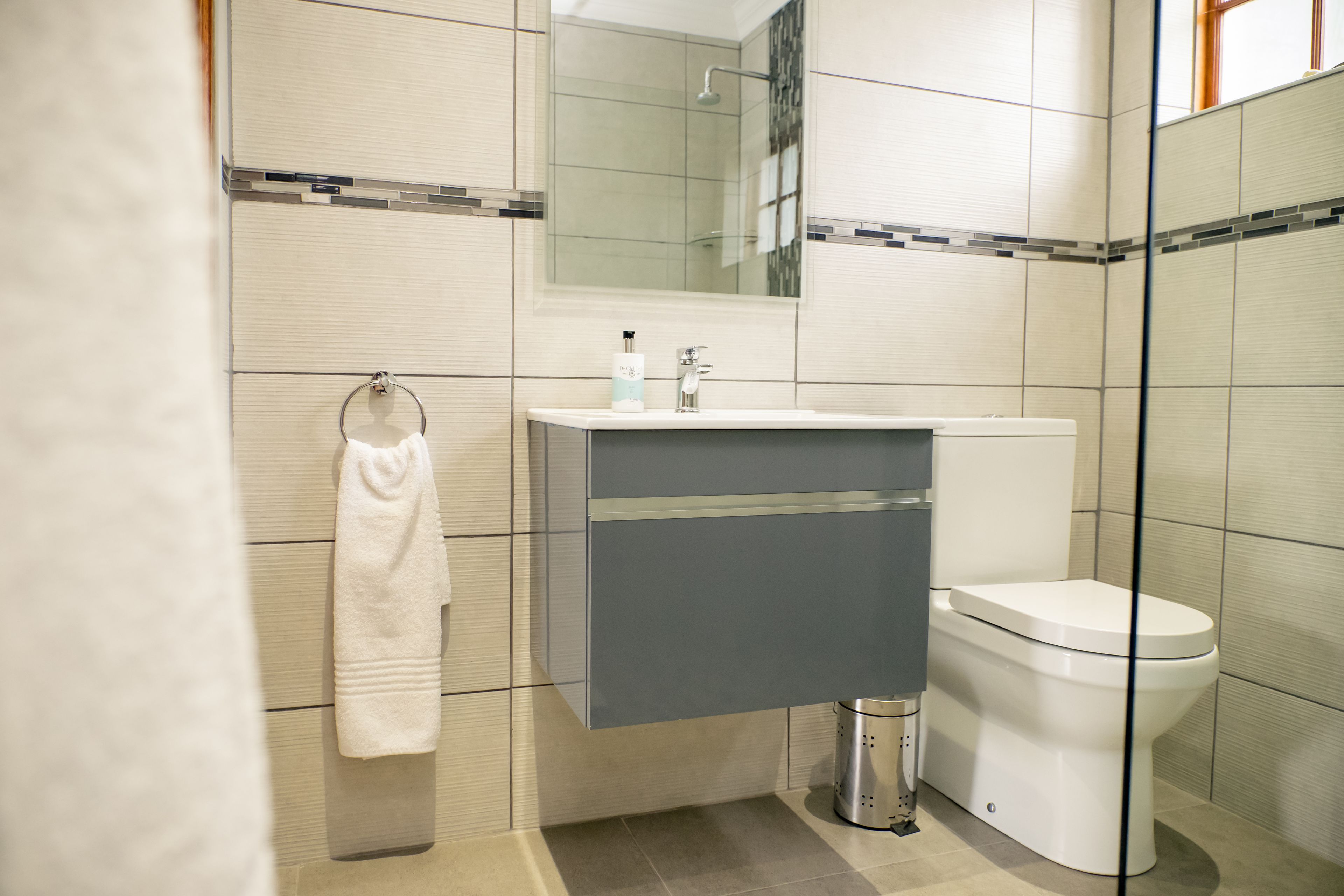 A modern bathroom with a toilet, sink, and towel rack.
