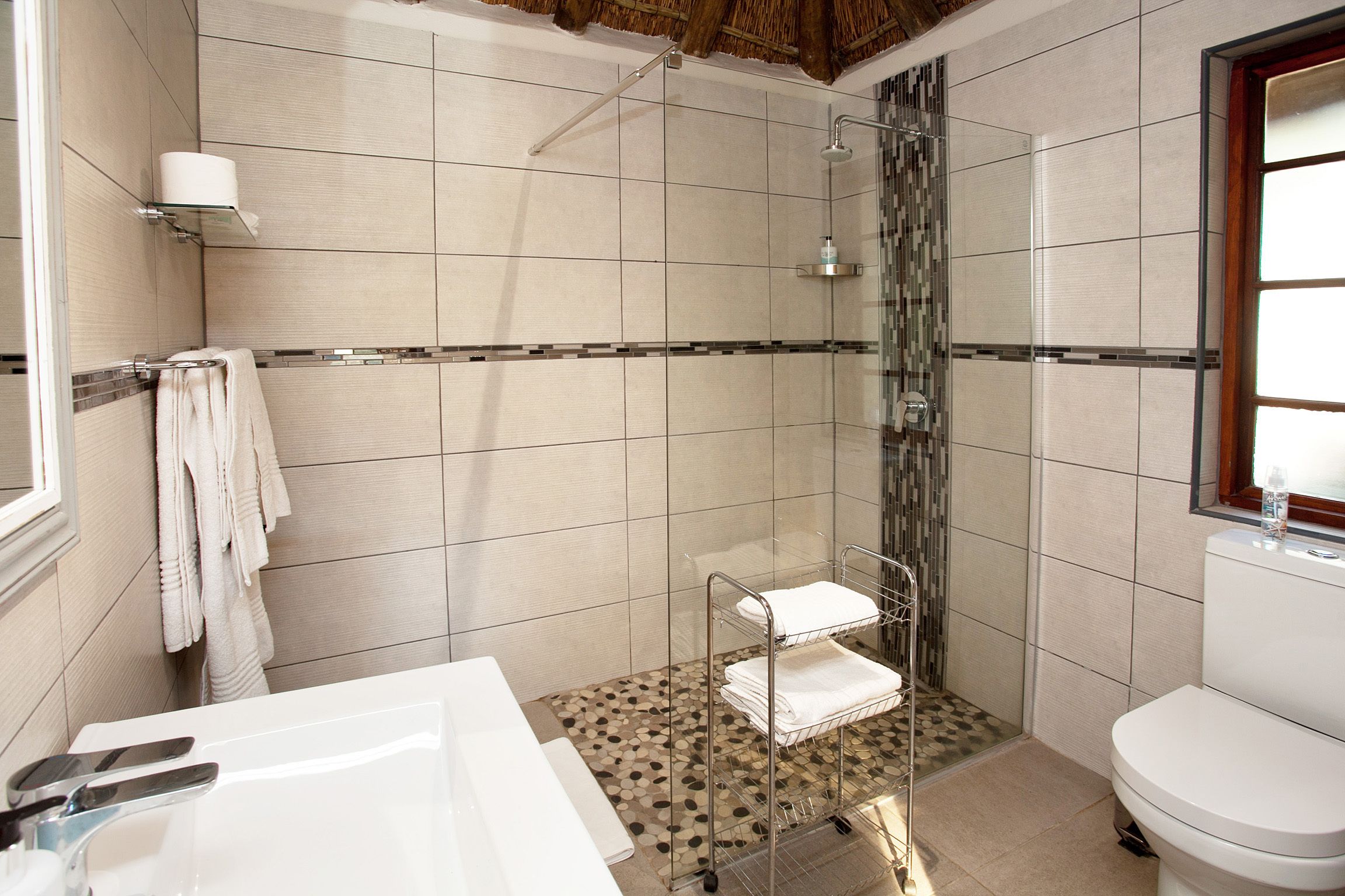 A bathroom with a shower, toilet, sink, and towel rack.