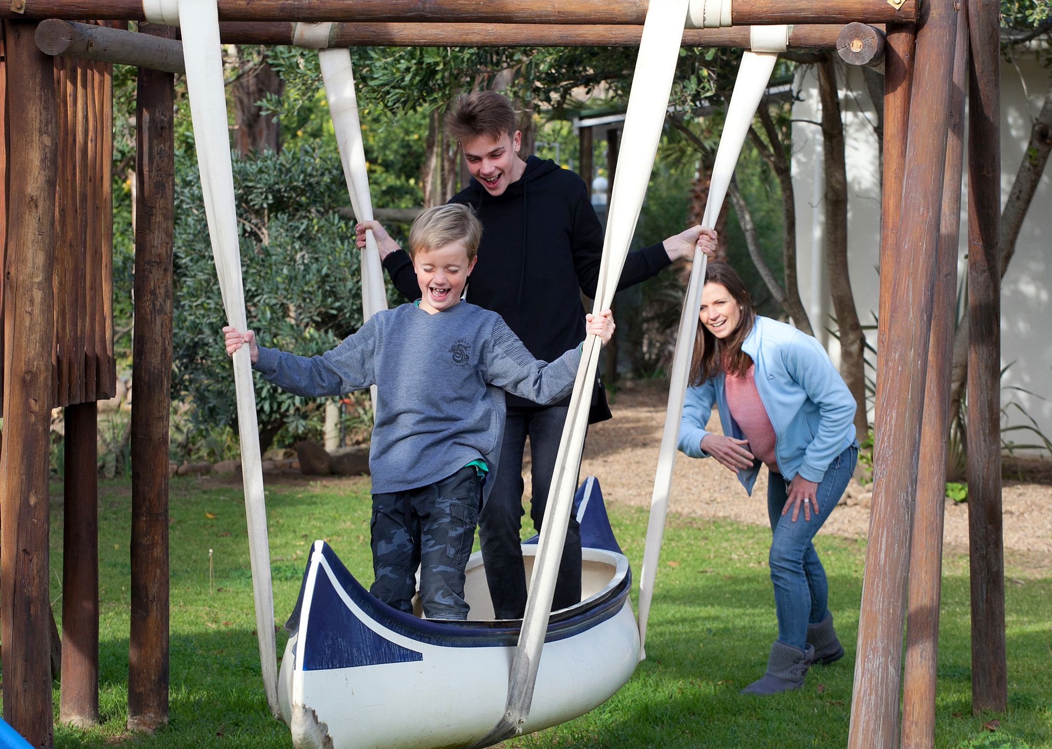 A wooden swing set with a swing seat shaped like a boat.