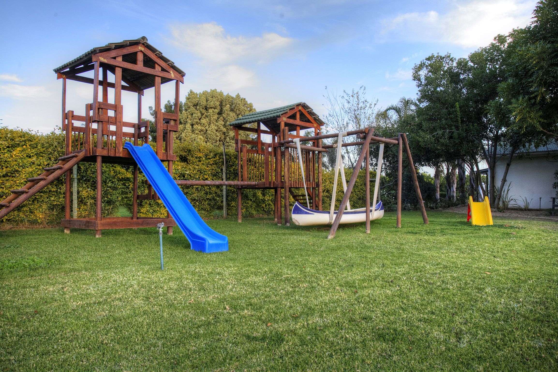 A playground with a slide, swings, and a small wooden structure.