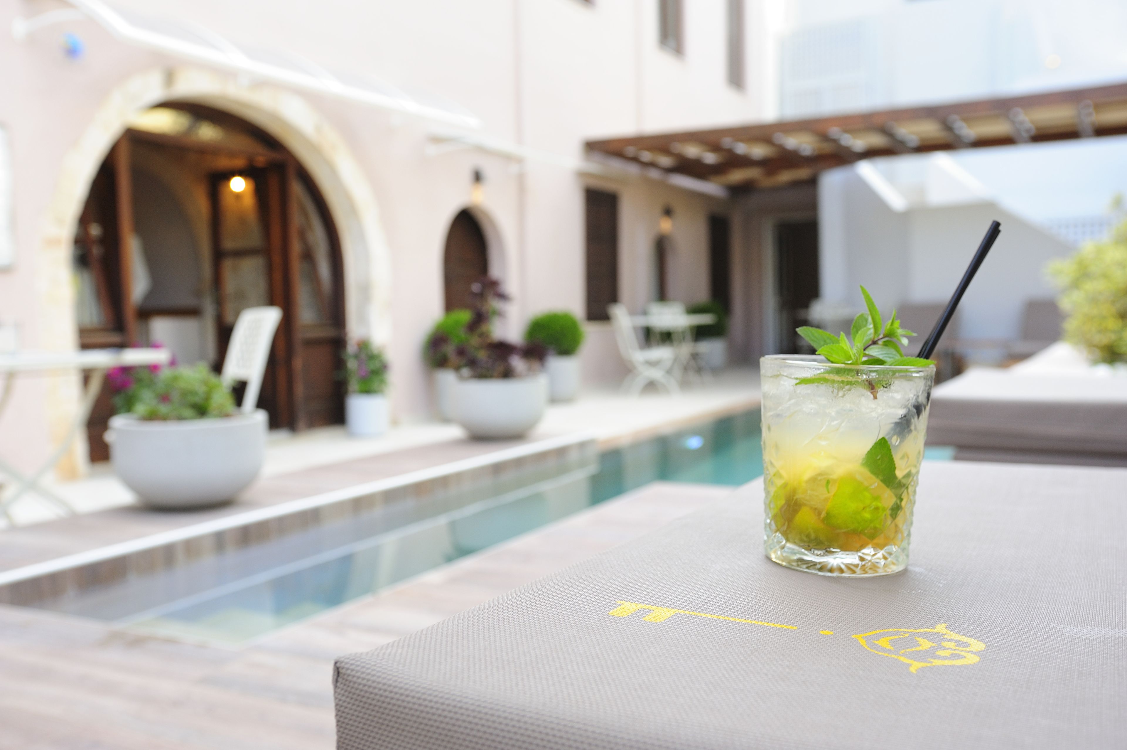 A glass of iced drink with mint on a poolside lounge chair.