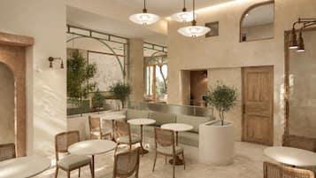 A modern interior with round tables and wicker chairs, a seating area with a cushioned bench, and a large wooden door.