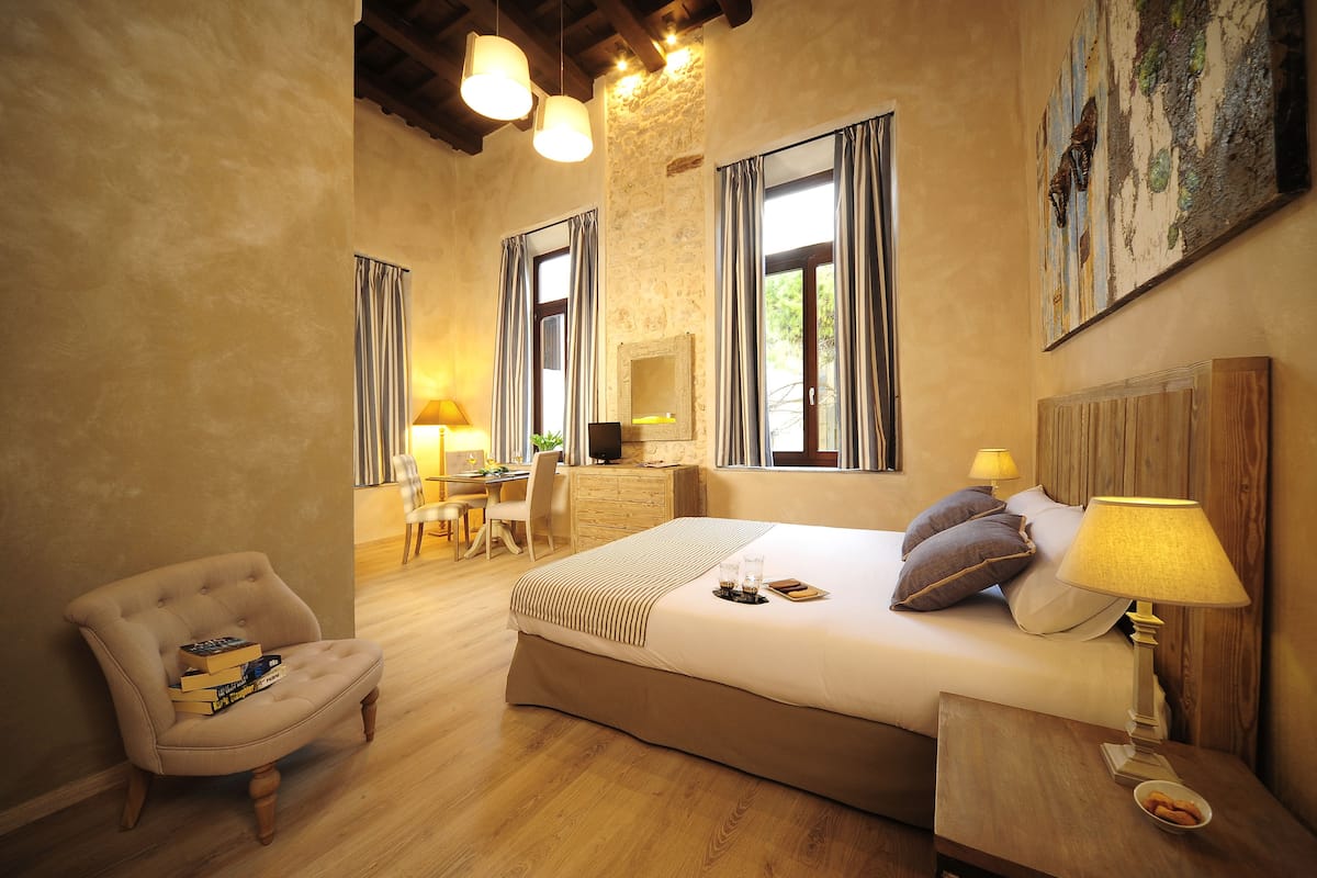 A cozy bedroom with a large bed, bedside tables, a chair, and a desk.