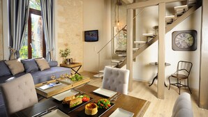 Una sala de estar moderna con sofá, mesa de comedor y una escalera que sube a un nivel superior.
