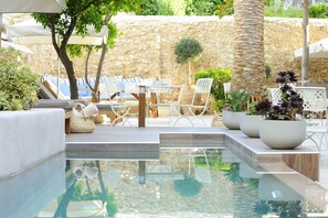 A pool area with lounge chairs, umbrellas, and potted plants. - Pepi Boutique Hotel - Adults Only (Rethymno)