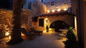 Un patio de piedra con sillones, una mesita y una planta en maceta.